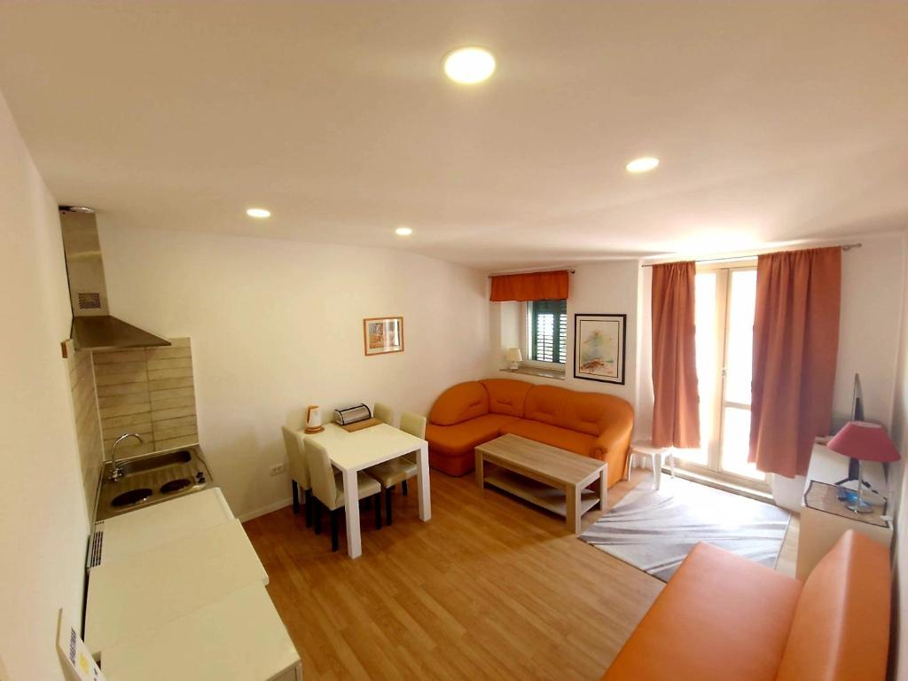 a living room with an orange couch and a table at Apartments Eis in Baška