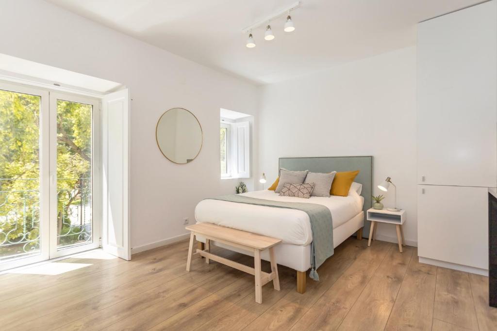 een witte slaapkamer met een bed en een spiegel bij Setúbal CityCenter Studios in Setúbal