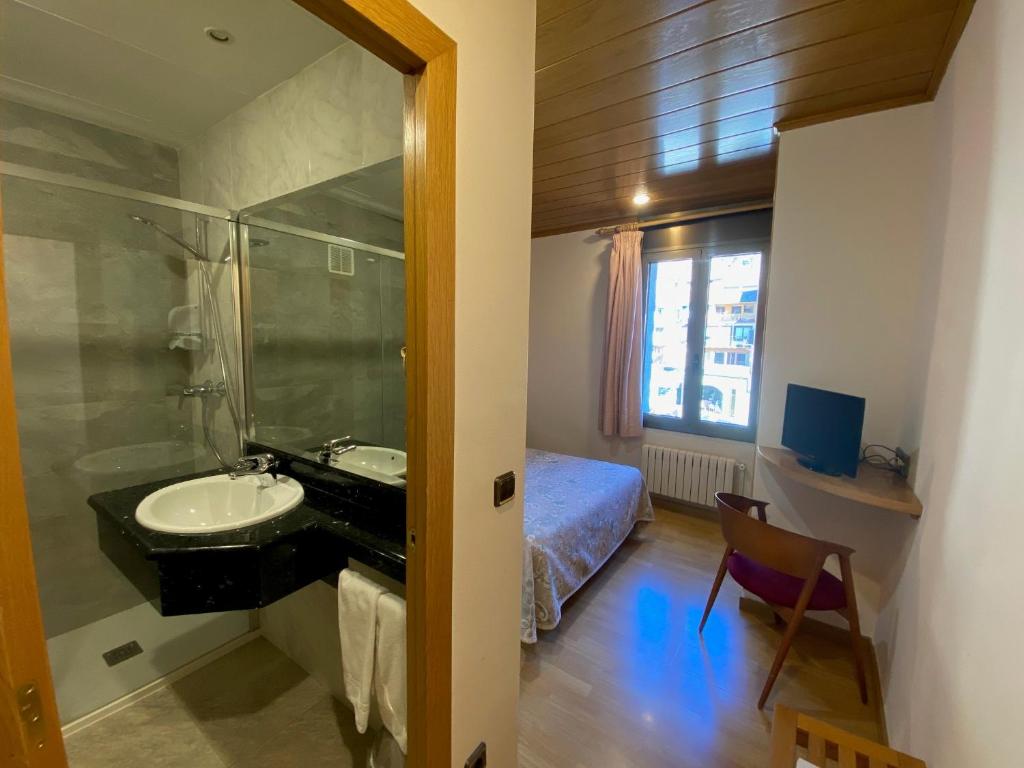 a bathroom with a sink and a bed and a mirror at Hotel Sant Antoni in Ribes de Freser