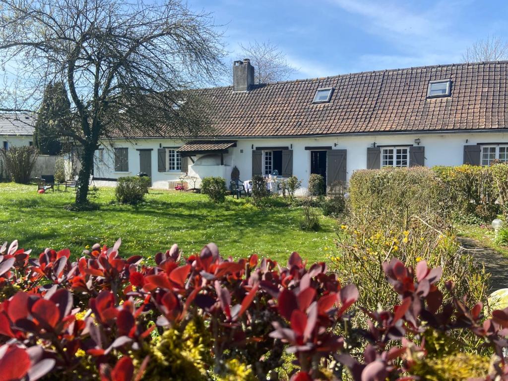 une maison blanche avec des fleurs rouges devant elle dans l'établissement Maison de Campagne Baie de Somme 17 couchages, à Tours-en-Vimeu