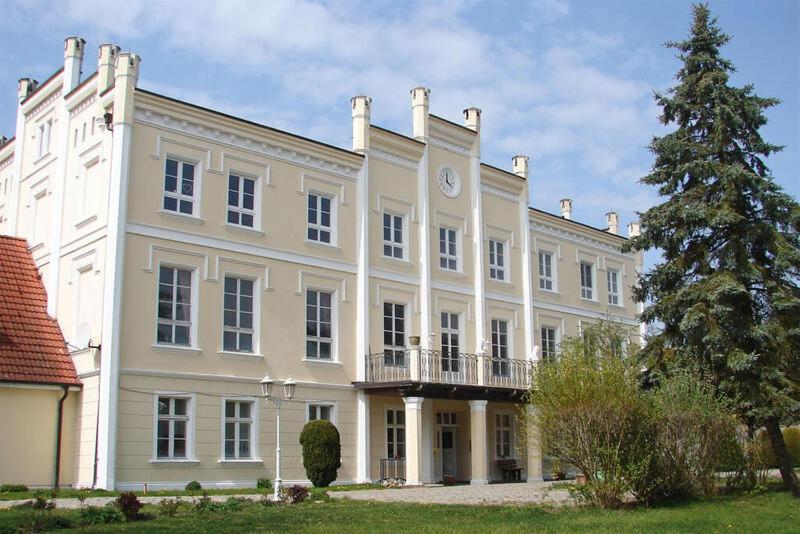 a large white building with a clock on it at Gemütliche Ferienwohnung für 3 Personen im Schloss Kastorf in Knorrendorf