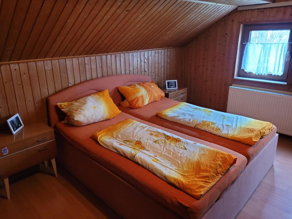 a bedroom with two beds with orange sheets and a window at Pizzeria Brar in Haina