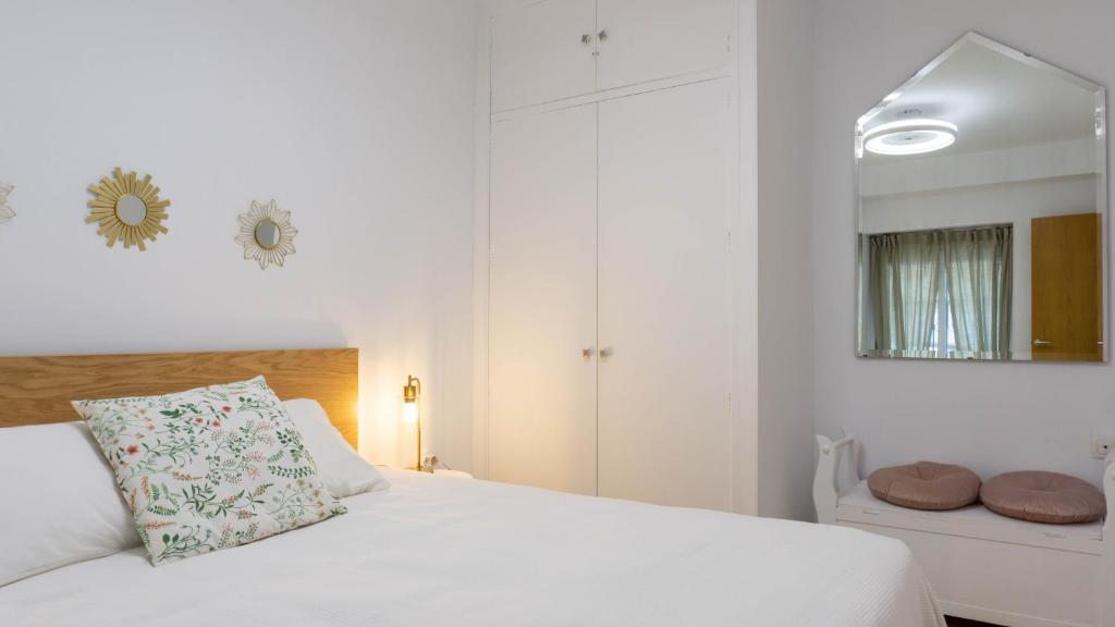 biała sypialnia z łóżkiem i lustrem w obiekcie Apartment Caleta Beach Málaga w Maladze