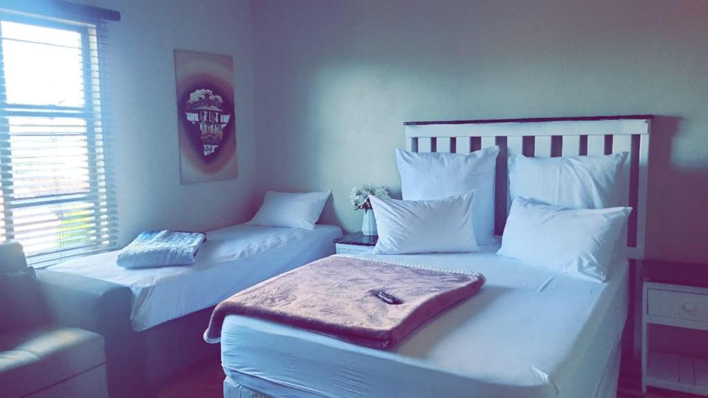 a bedroom with two beds with white pillows at The Vine Guest House Potchefstroom in Potchefstroom
