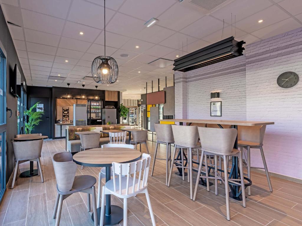 - un restaurant avec des tables et des chaises dans une salle dans l'établissement B&B HOTEL Landerneau Bois Noir, à Landerneau