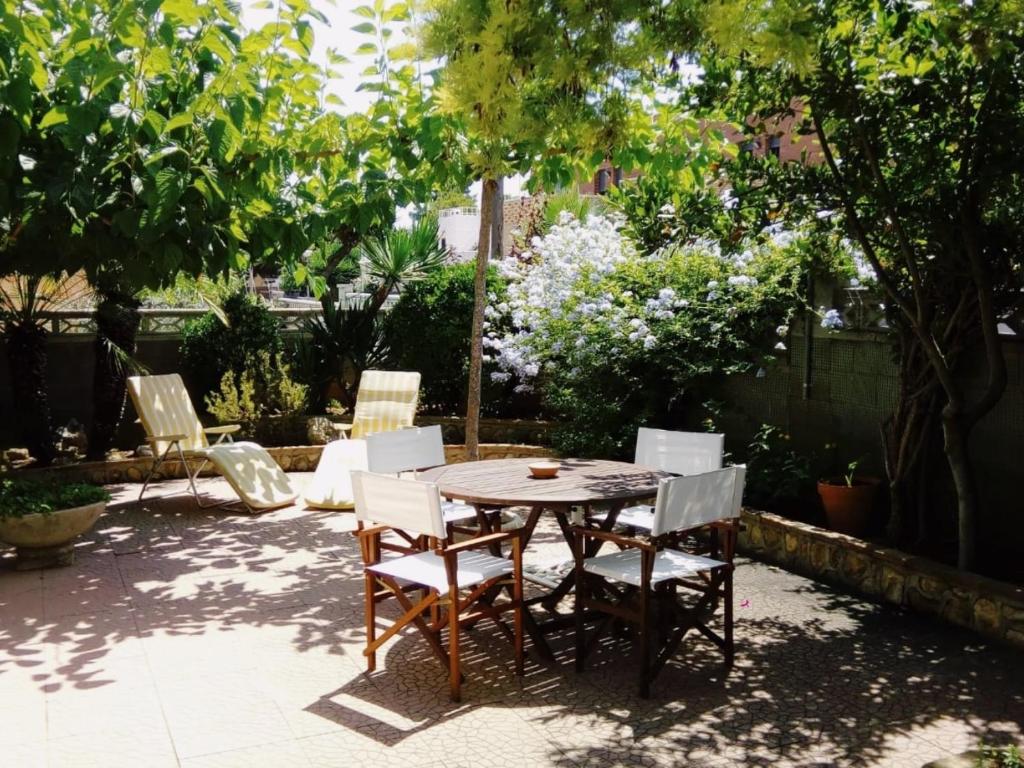 a table and chairs in a garden with trees at Llar Montagut Torredembarra in Torredembarra