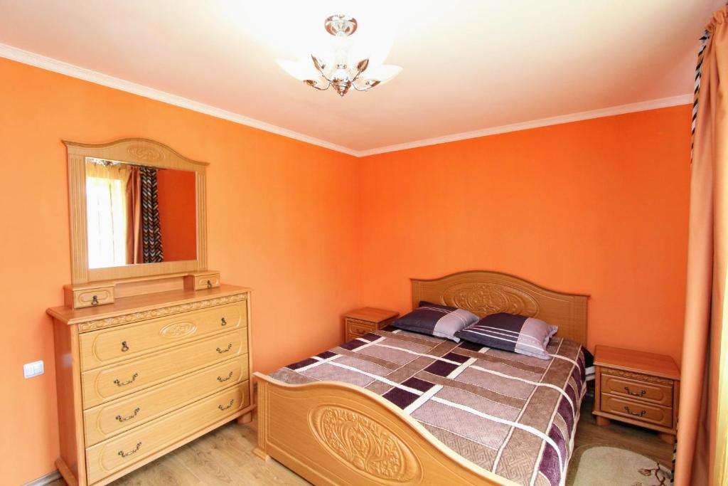 a bedroom with orange walls and a bed and a dresser at Cottage "Kliverent" in Yaremche