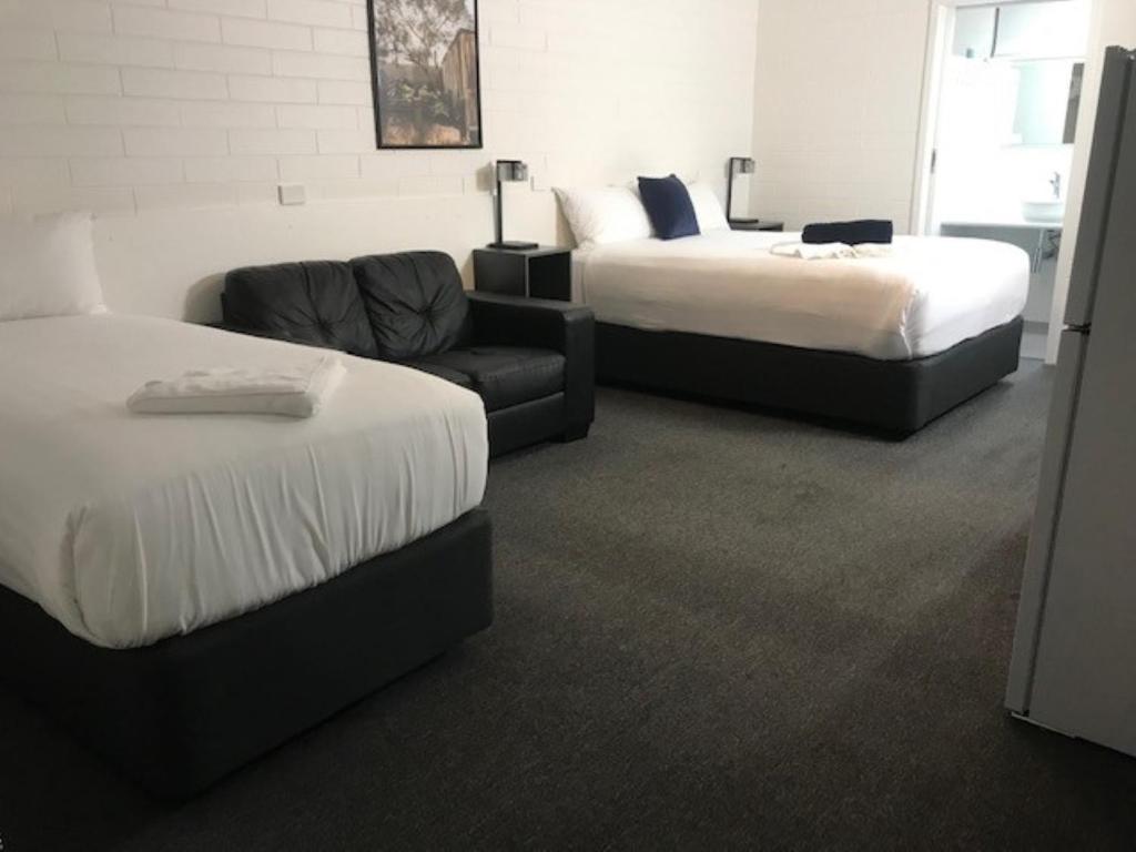 ミルデューラにあるVineland Motel Milduraのベッド2台とソファが備わるホテルルームです。