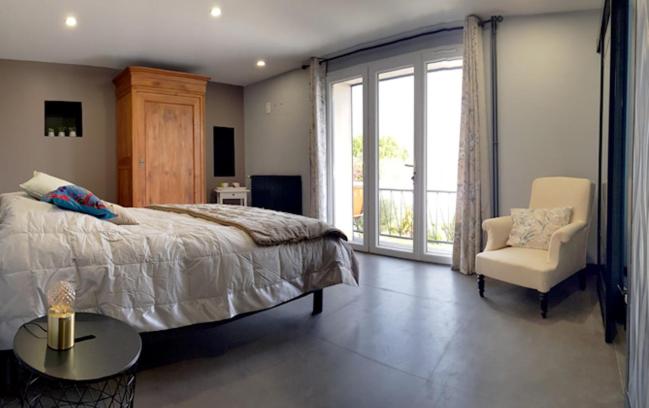 ein Schlafzimmer mit einem Bett, einem Stuhl und einem Fenster in der Unterkunft Aux portes des iles in Saint-Just