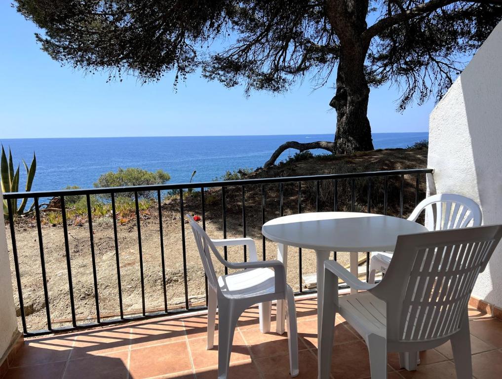 einen Tisch und zwei Stühle auf einem Balkon mit Meerblick in der Unterkunft APPARTEMENTS SOL y MAR - Cala Llevado 2 in Tossa de Mar