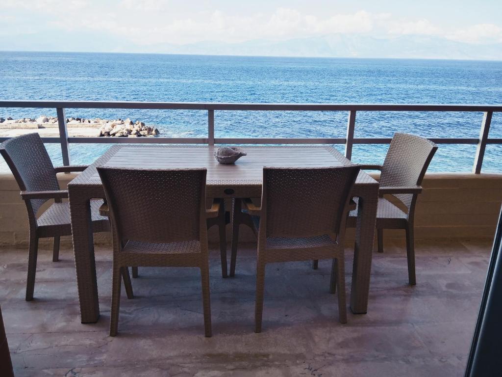 SKY AND SEA APARTMENT في غزيلوكاسترون: طاولة وكراسي على شرفة مطلة على المحيط