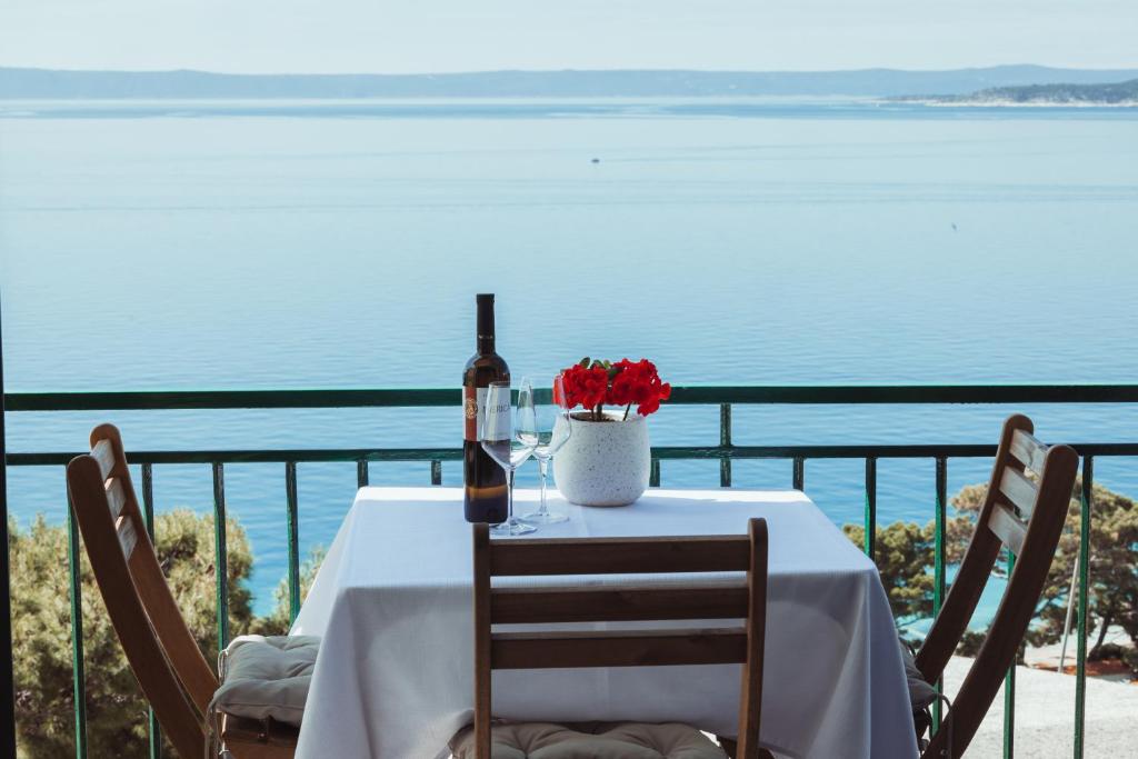 a table with a bottle of wine and flowers on a balcony at Apartmani Stipe Brela in Brela