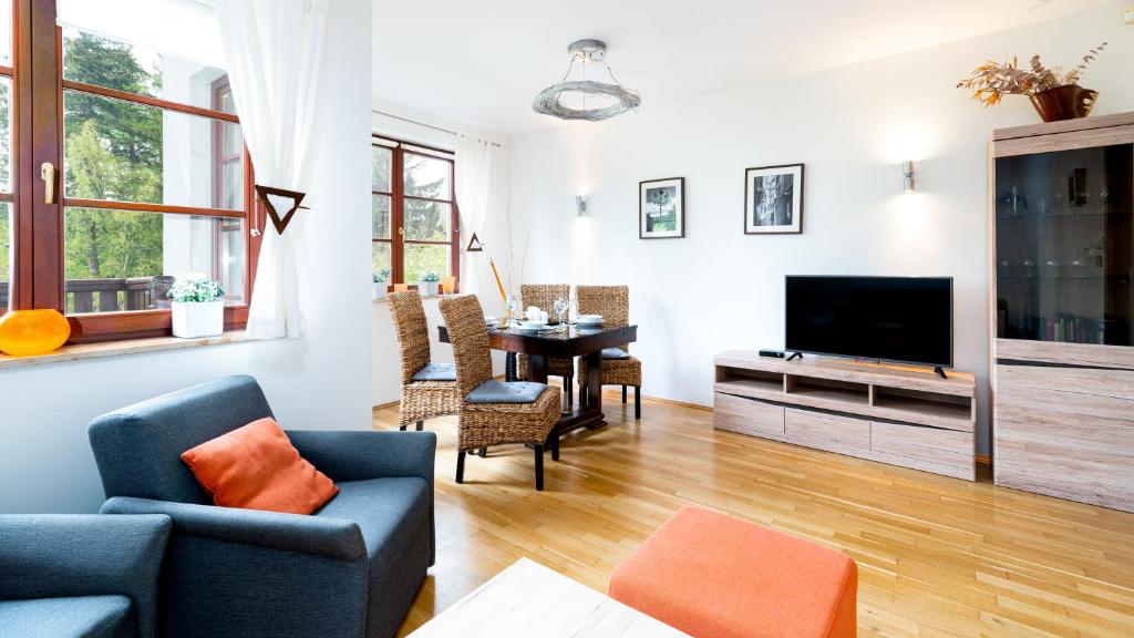 ein Wohnzimmer mit einem Sofa und einem TV in der Unterkunft Apartamenty Sun & Snow Okrzei Karpacz in Karpacz