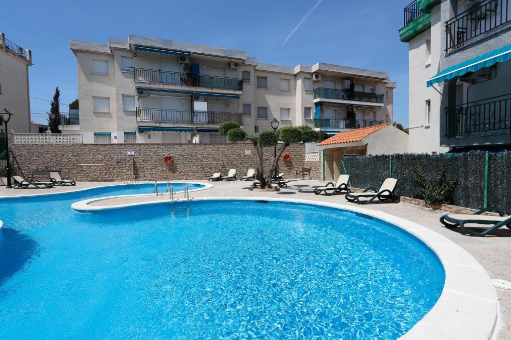 Una gran piscina azul frente a un edificio en AT052 Planta baja con piscina, tan solo 600m de la playa, en Torredembarra