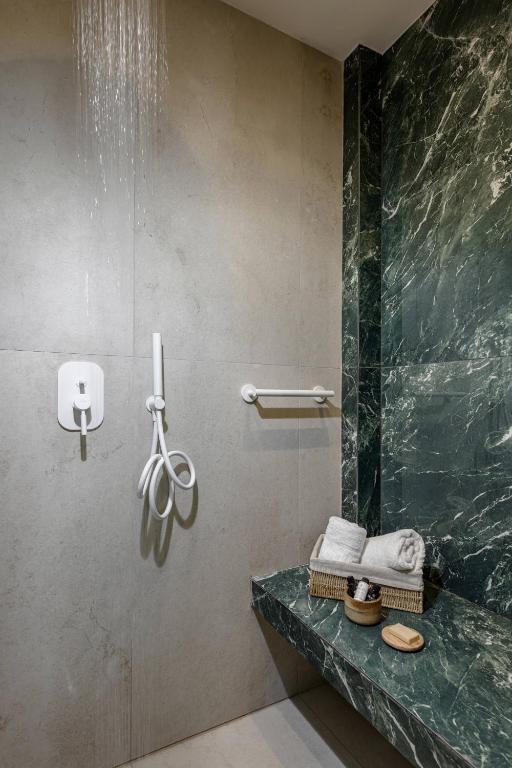 a bathroom with a shower with a green marble wall at Hotel Villa Natassa in Skala Rachoniou