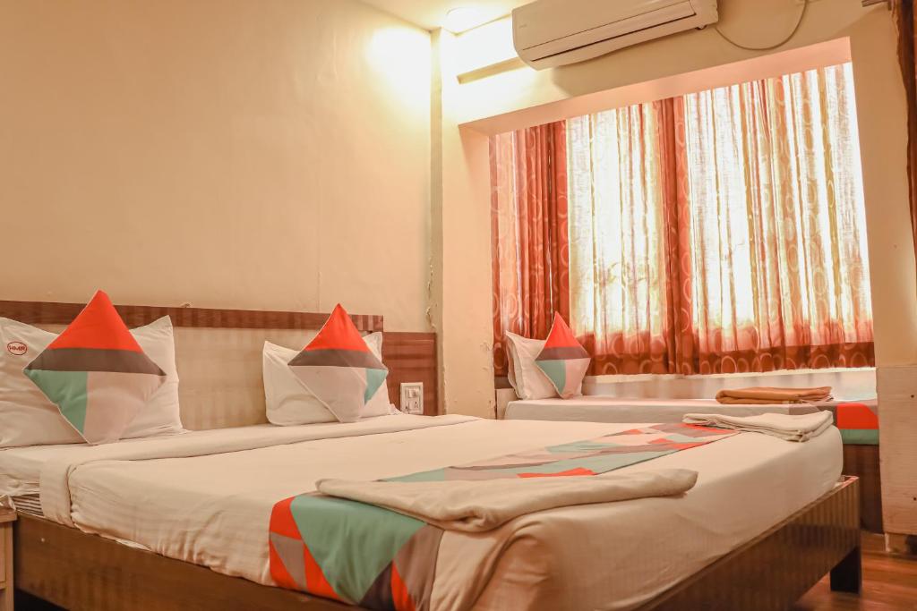 a bedroom with two beds and a window at Hotel Mukesh Residency in Pune