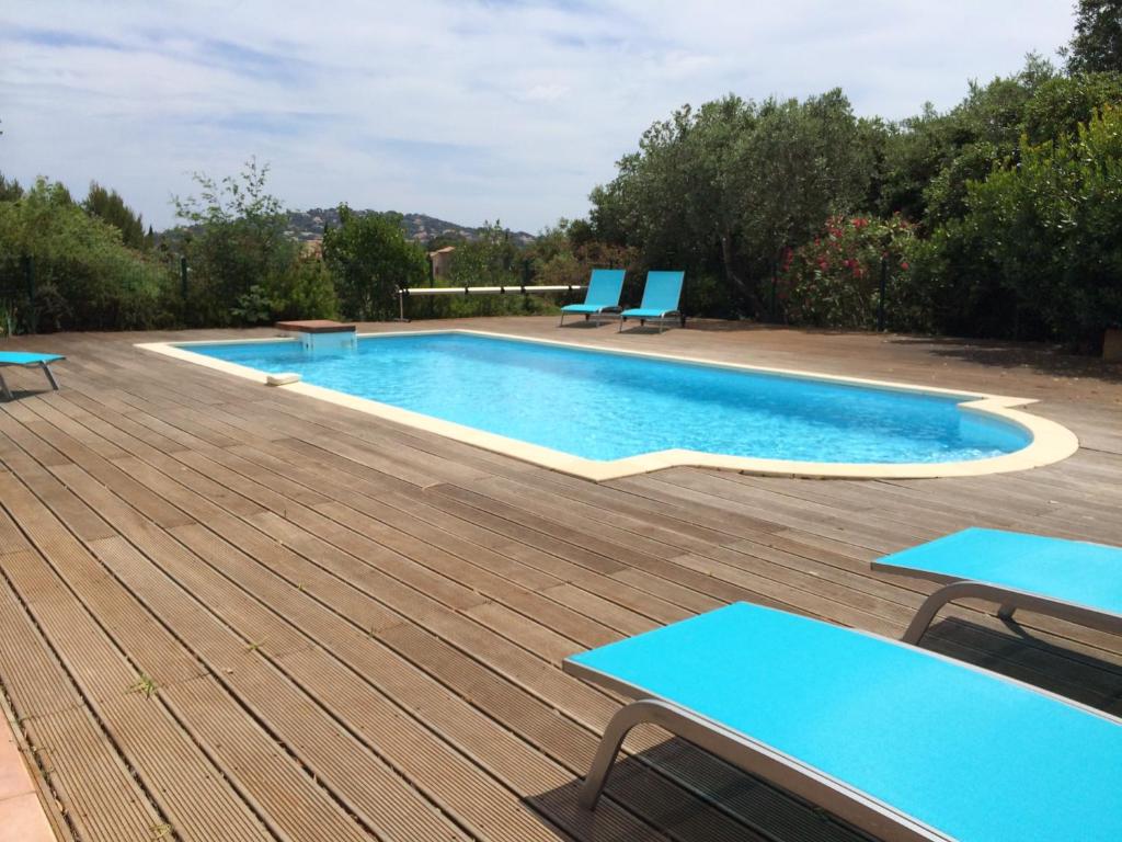 une piscine avec des chaises bleues sur une terrasse en bois dans l'établissement Villa Romuald, à Sainte-Maxime