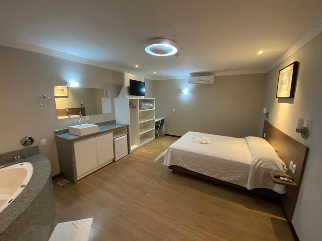 a bedroom with a bed and a sink and a bathroom at Hotel Raul's in Gaspar
