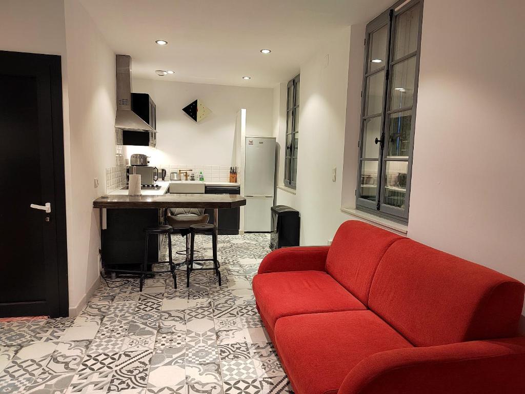un salon avec un canapé rouge et une cuisine dans l'établissement Appartement charmant à Béziers, terrasse commune, 40 m², à Béziers
