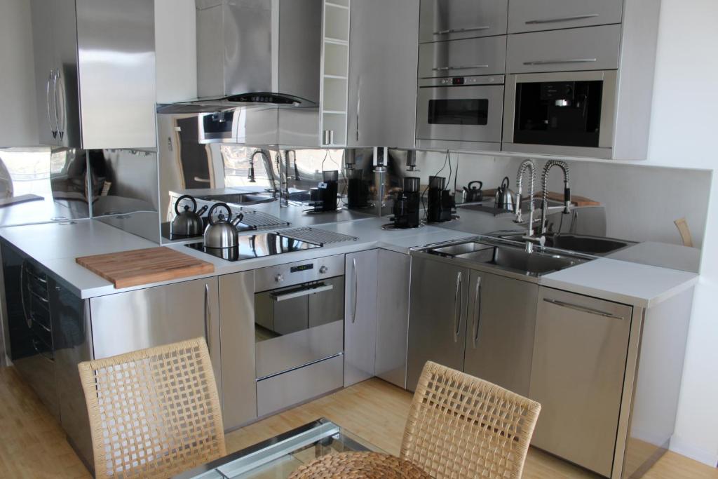 eine Küche mit Küchengeräten aus Edelstahl und 2 Stühlen in der Unterkunft Apartmán Relax so saunou a jakuzzi in Námestovo