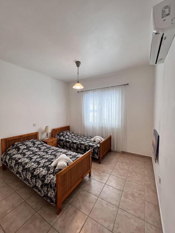 a bedroom with two beds and a tv in it at Pafia Sunbeach Townhouse in Paphos
