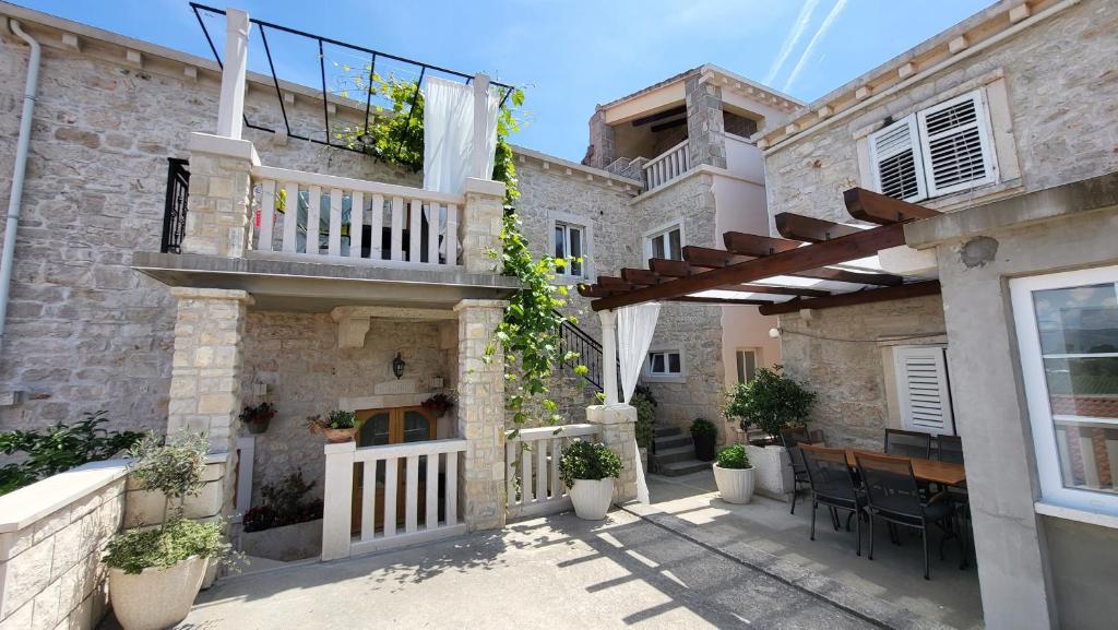 patio di una casa con tavolo e balcone di Stone House Apartments Didini Dvori Lumbarda a Lumbarda (Lombarda)