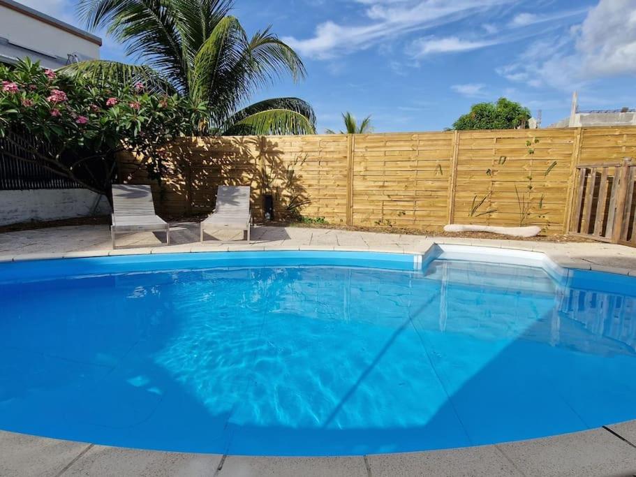 a large blue swimming pool in front of a fence at Villa Eden, à 400 mètres de la plage du Souffleur in Port-Louis