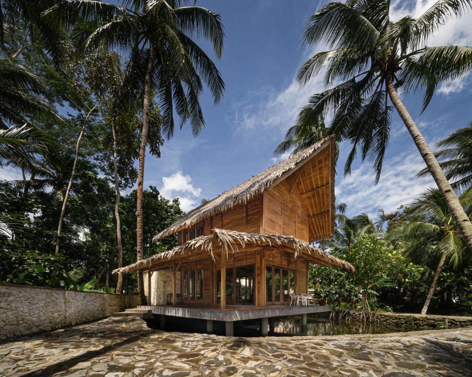 a house on the beach with palm trees at Cay's House Batukaras in Batukaras