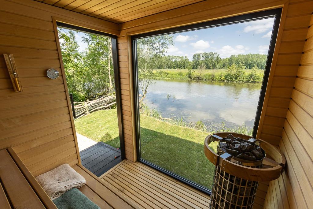 um alpendre com vista para um lago em Leie Villa II - by the river with sauna & jacuzzi em Deinze