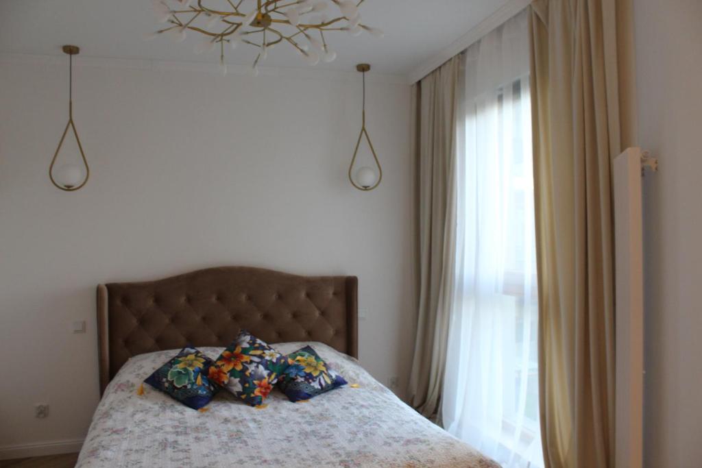 a bedroom with a bed with pillows and a window at Gdańsk Porto Apartments in Gdańsk