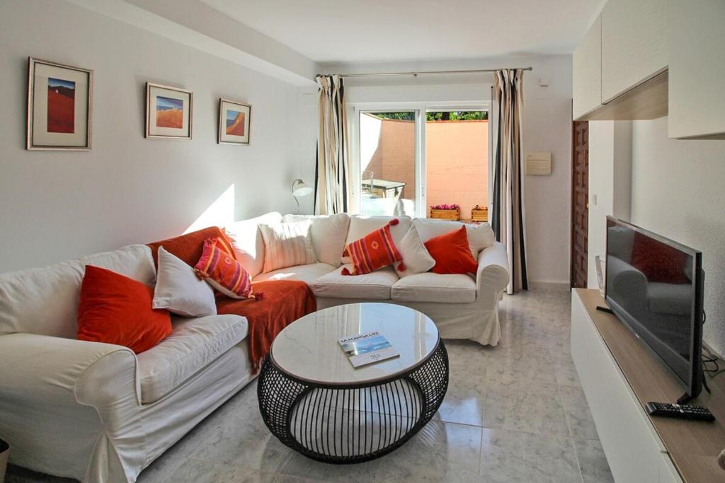 a living room with a couch and a table and a tv at Ground Floor Bellaluz Apartment - La Manga Club in Atamaría