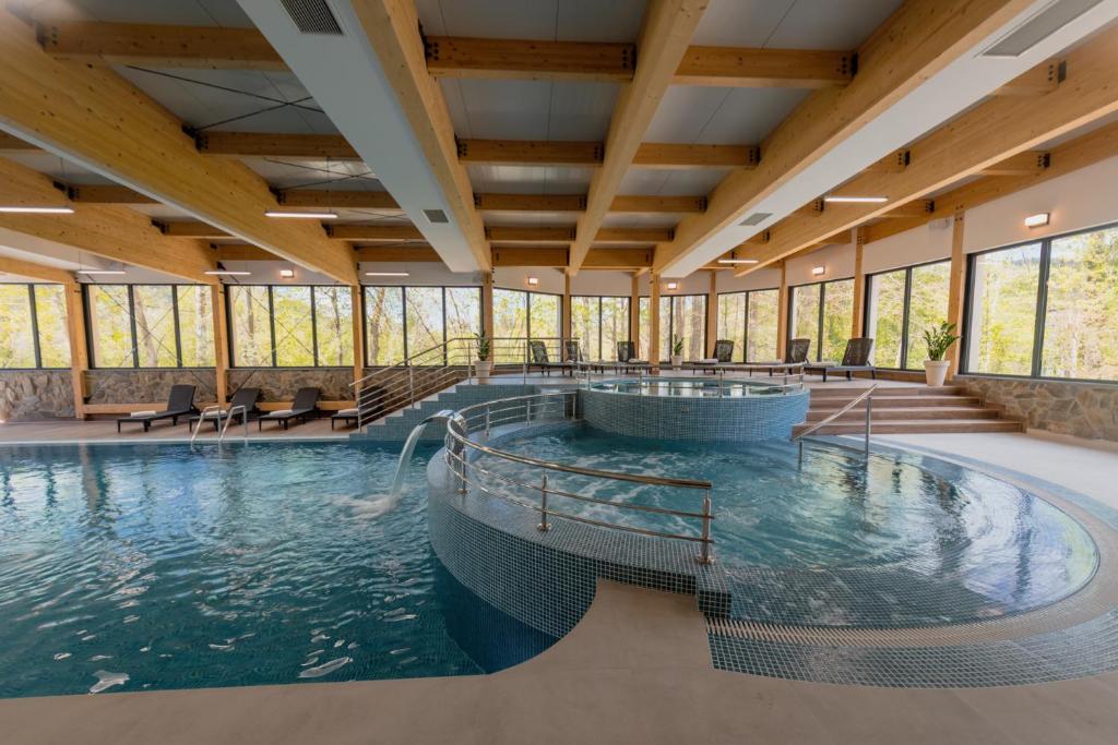a swimming pool in a large building with windows at Country Club Żywiec Hotel i Domki Całoroczne in Żywiec