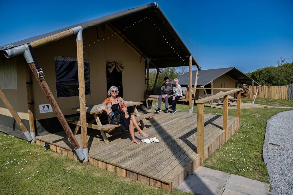 a woman sitting on a porch of a house at Little Pig Glamping in Bude