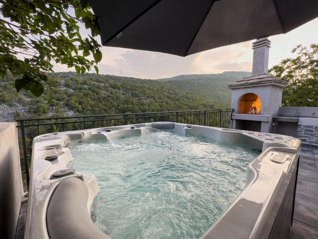 a hot tub on a deck with a view of a mountain at Holiday Home Vrkic with Hot Tub in Omiš