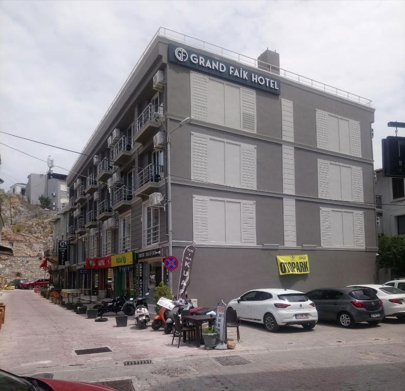 a grand park hotel with cars parked in front of it at Grand Faik Hotel in Çeşme