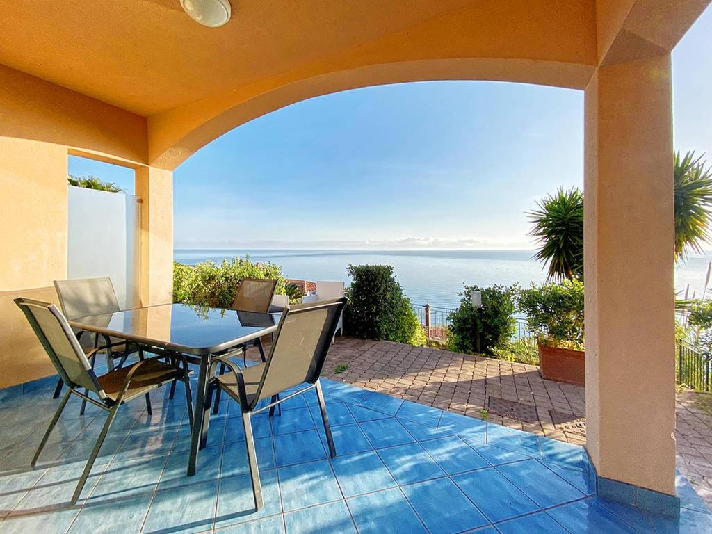 a patio with a table and chairs and the ocean at Grand Bleu Magarà in Cefalù