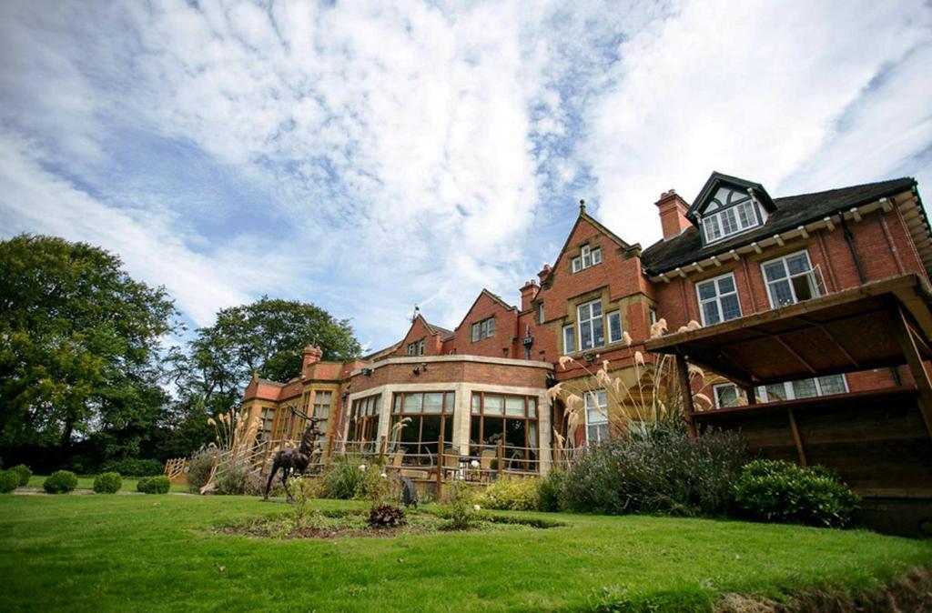 ウォルヴァーハンプトンにあるThe Mount Country Manor Hotel & Golf Wolverhamptonの緑豊かな芝生の大煉瓦造りの家