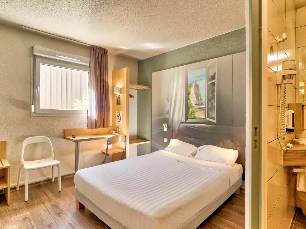 um quarto de hotel com uma cama, uma secretária e uma janela em B&B HOTEL Clermont-Ferrand Sud Aubière em Aubière