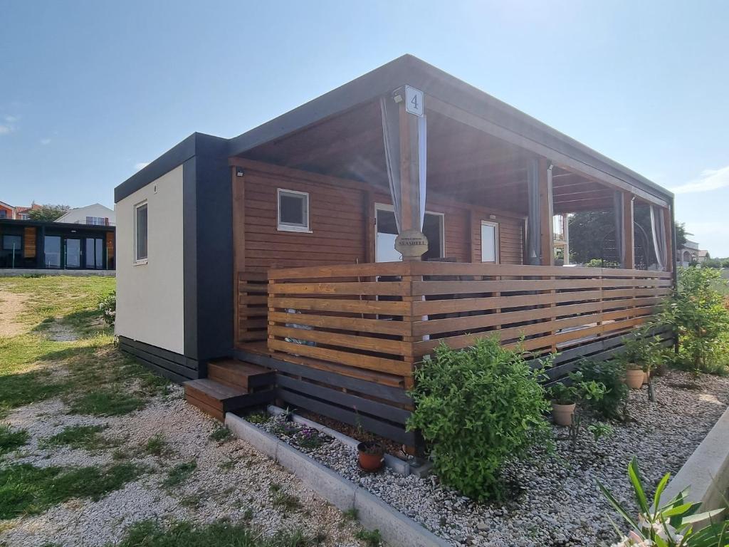 a tiny house with a large wooden deck at Mobile house Seashell in Pakoštane