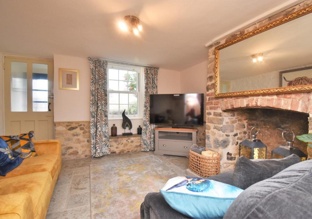 a living room with a couch and a fireplace at Bluebell Cottage - Seaton in Seaton