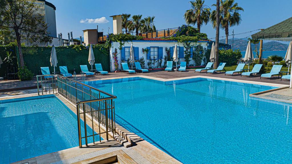 a large swimming pool with chairs and a house at Uras Beach Hotel in Fethiye