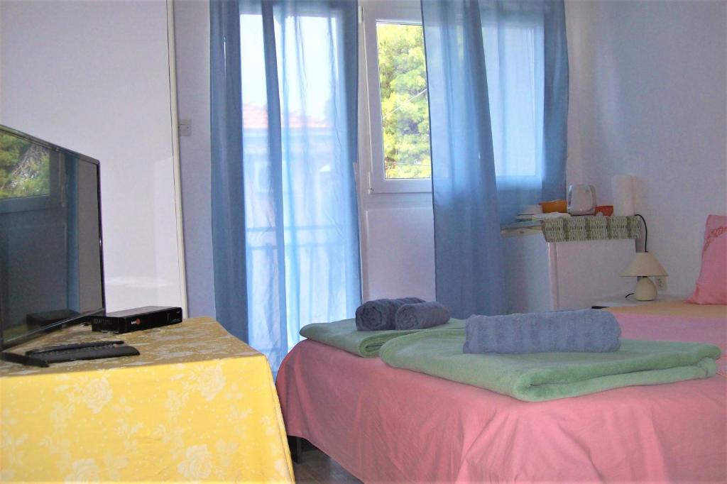 a room with two beds and a tv and a window at Dinka's Apartment in Stari Grad