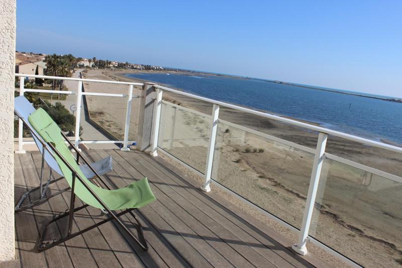 a couple of chairs sitting on a deck next to the beach at Superbe appartement vue Mer - Gruissan 6LB42 in Gruissan