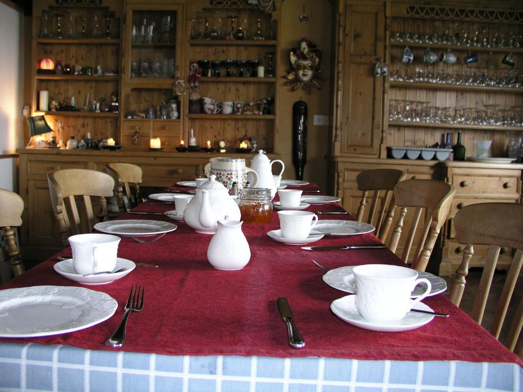 una mesa larga con platos, tazas y utensilios en Lakeland Midsummer Lakehouse, en Oughterard