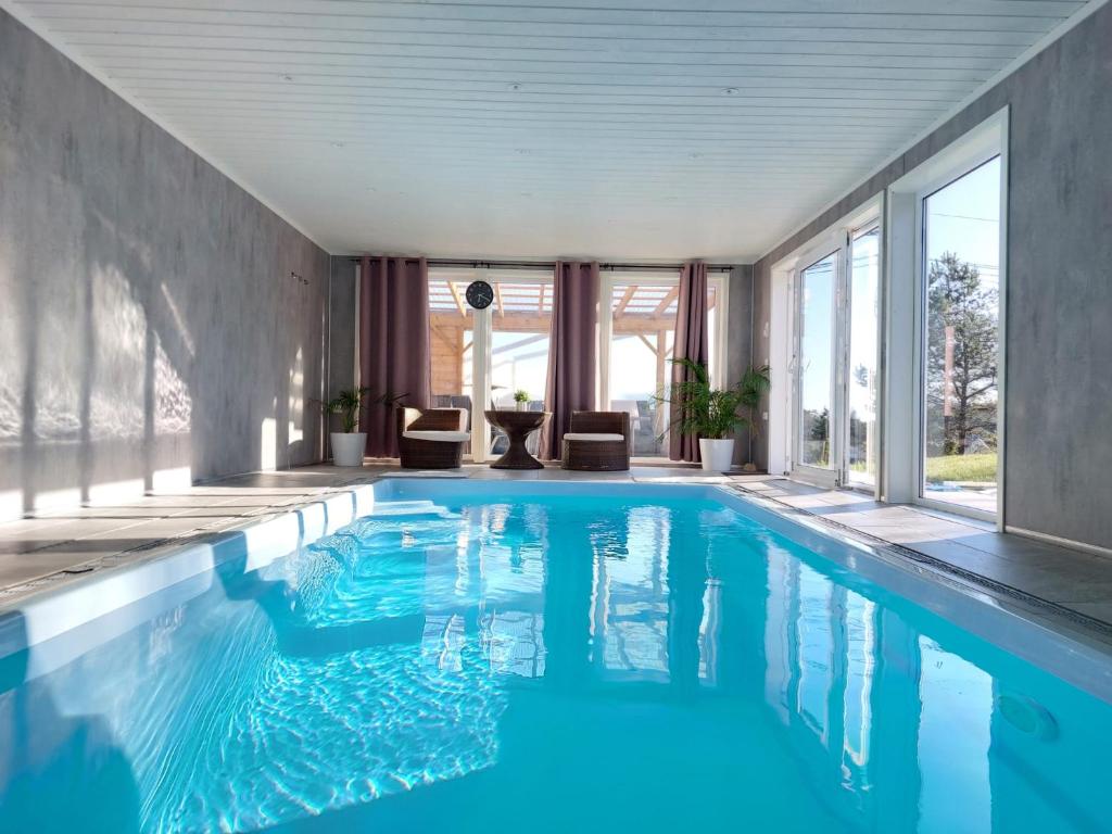 una piscina de agua azul en una habitación con ventanas en Cosy family home with pool en Grimstad