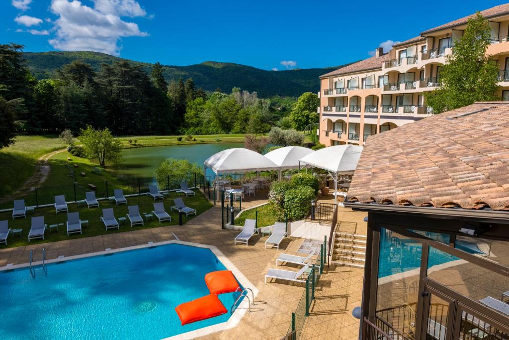 een buitenzwembad met stoelen en een hotel bij Domaine Les Sources de Dieulefit in Dieulefit