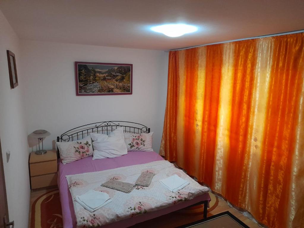 a small bedroom with a bed with an orange curtain at Apartment Mia's Home in Orşova