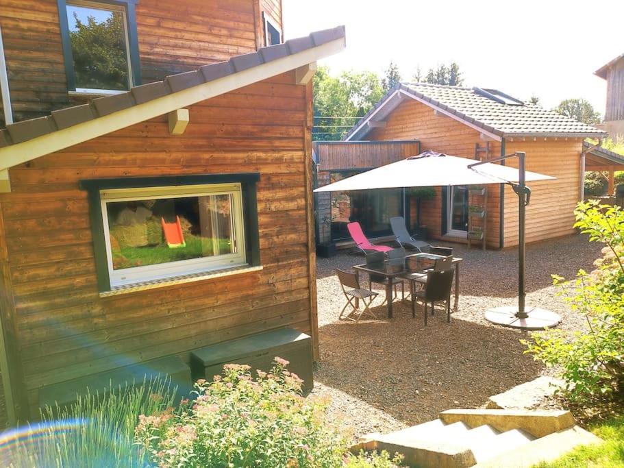 - une terrasse avec une table et un parasol à côté d'une maison dans l'établissement La Salixienne maison 6/7 pers, à Saulcy-sur-Meurthe