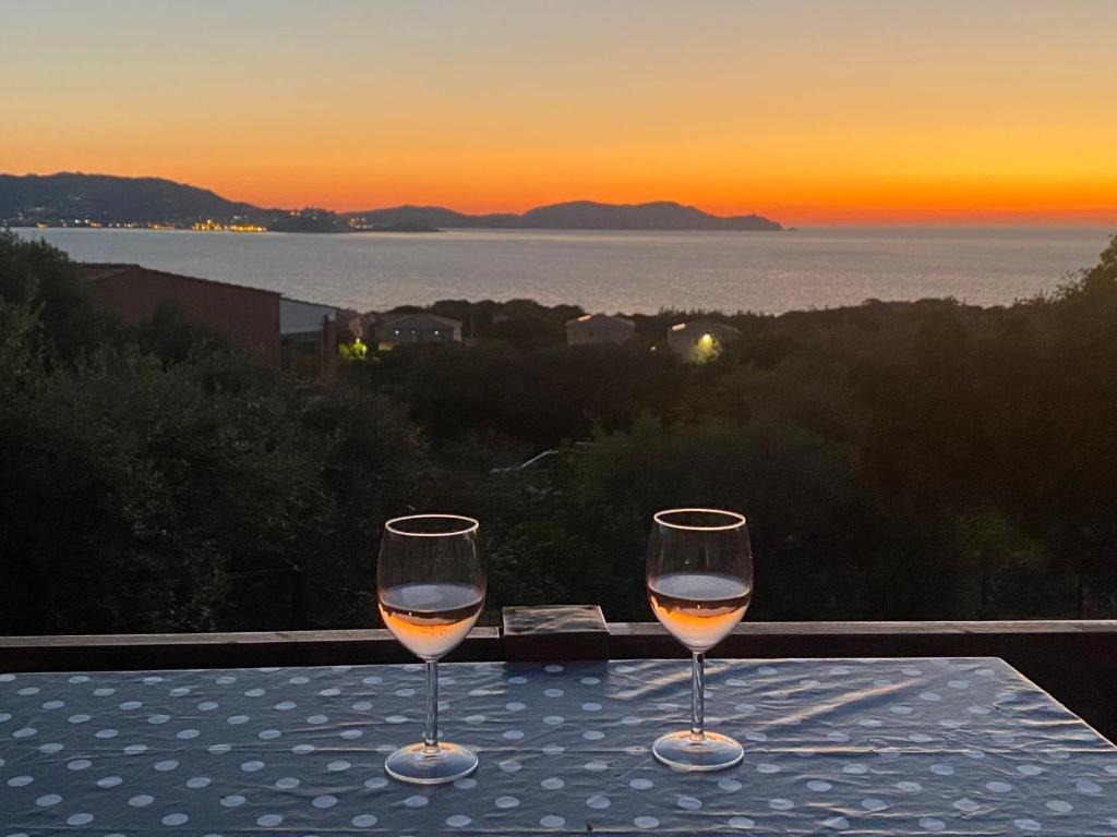 - deux verres de vin assis sur une table au coucher du soleil dans l'établissement Calvi Lumio location face mer, à Lumio