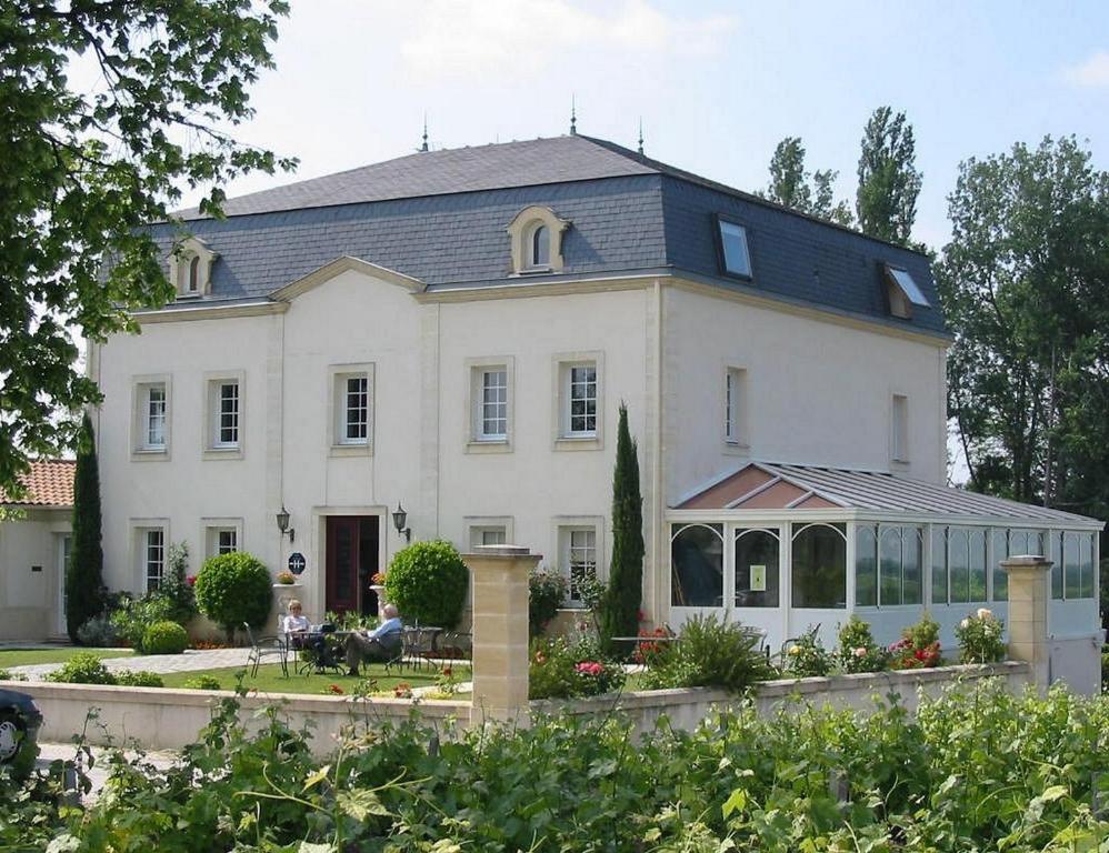 une grande maison blanche avec une véranda en face de celle-ci dans l'établissement Hôtel de Margaux, à Margaux